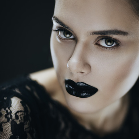 Fashion portrait of young brunette woman with black lips. Shallow depth of fieldの写真素材