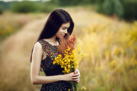 Artistic portrait of young gorgeous brunette on green meadow. Shallow depth of fieldの写真素材