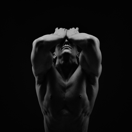 Athletic young shirtless muscular man on blackの写真素材