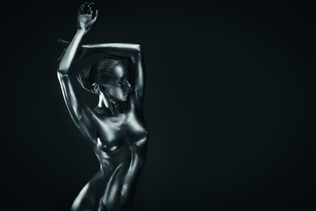 Young fit athletic nude woman in silver body paint posingの写真素材