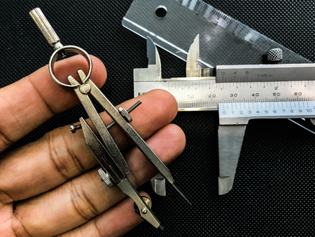 Compasses , ruler , Vernier Caliper used for the drawing , on the texture black background represent the tool and equipment concept related idea.の写真素材
