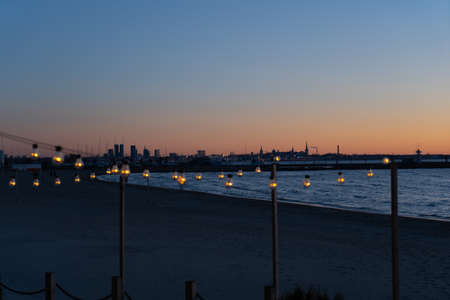 Close up of the glowing light bulbs at the beach cafe terrace. Sun is setting in the blurry abstract background.の写真素材