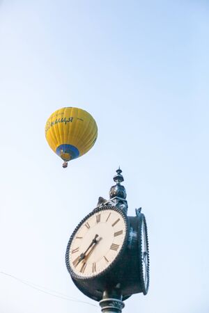 hot air balloon in flight and old clock on blue sky