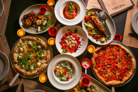Top down view on enormous buffet of delicious freshly prepared european cuisine and pizza with menuの写真素材