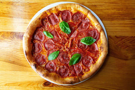 Delicious salami pizza with basil and spices on table top viewの写真素材