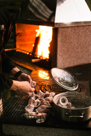 Close-up man hand putting big tasty juice raw t-bone beef steak on grill at barbecue with bright hot burning charcoal at brazier. BBQ meal cooking backgroundの写真素材