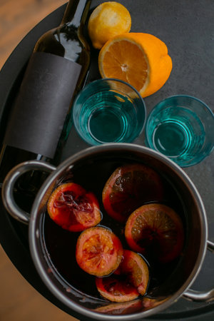 Christmas mulled red wine with the addition of spices and citrus fruits in a pot on a rustic wooden table, top view. Pot of mulled wine, traditional Christmas drink.の写真素材