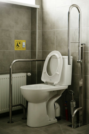 Modern accessible toilet with grab bars, a wall-mounted shower seat, and toilet designed for...