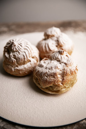 Decorating profiteroles with powdered sugar. Eclair with icing sugarの写真素材
