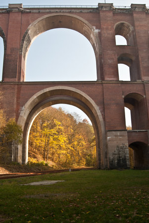 detail of Elstertalbrucke brick bridge with colorful autumn forest on the background and clear sky near Plauen cityのeditorial素材