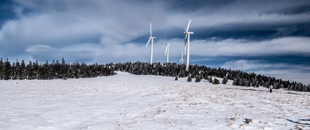 Steinriegel hill with wind turbines, snow and blue sky with clouds in Stuhleck mountain ridge in Fischbacher Alpen in Styria during winterの写真素材