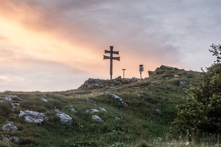 Klak hill eith cross, mountain meadow and limestone stones in Mala Fatra mountains in Slovakia during sunset with colorful skyの写真素材