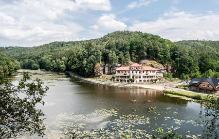 Harasov pond with few houses and nice landscape around with road, rocks and hills covered by forest in CHKO Kokorinsko in Czech republic near Melnik cityの写真素材