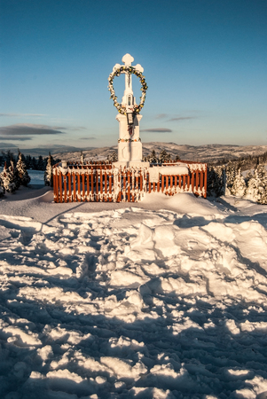 crucifix statue in winter snowy countryside with hills on the background, trees and clear sky near Koniakow village in Beskid Slaski mountains in Polandの写真素材