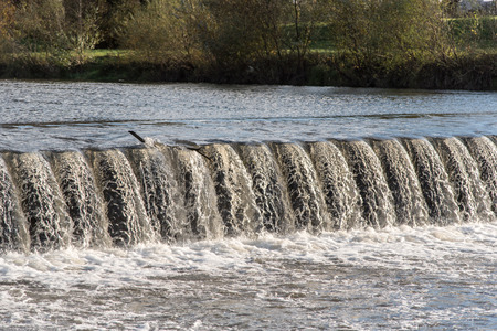 weir on Olse river in Karvina city in Czech republic with trees and grass on the backgroundの写真素材