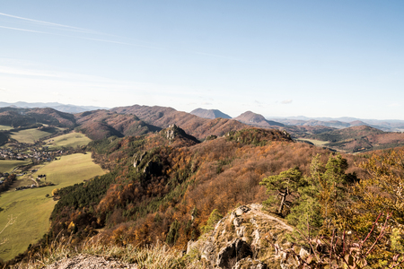 View from Stefanikova vyhliadka in Sulovske skaly mountains with hills covered by colorful forest and rural landscape with Sulov village during autumn day with clear skyの写真素材