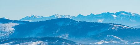 Zaoadne Tatry mountains from Brestova to Velka Kamenista peak and nearer hills of Beskid Zywiecki mountains from Magurka Wislanska hill in Beskid Slaski mountains in Poland during beautiful winter dayの写真素材