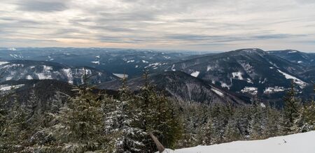 Winter mountain panorama with Sance water reservoir and many snowcapped hills from hiking trail near Lysa hora hill summit in Moravskoslezske Beskydy mountains in Czech republicの写真素材