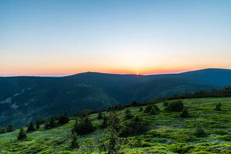 Sunset with cooorful sky and Vozka hill with rock formation from Cervena hora hill in Jeseniky...