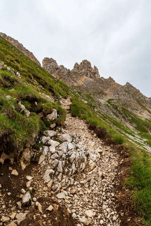 Latemar mountain group with sttep meadow, hiking trail and rocky mountain peaks on the background in...