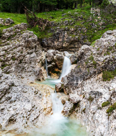 Mountain creek with small waterfall, rocks, stones and meadow around in Val Lasties valley near Passo Sella in Dolomites mountains in Italyの写真素材