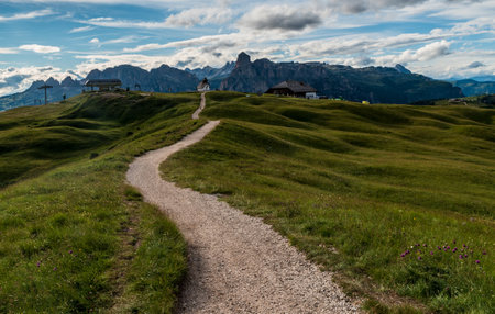 Pralongia covered by, meadow with trail, lift station and hut and higher rocky peaks on the background above Corvara in Dolomiti mountains in Italyの写真素材