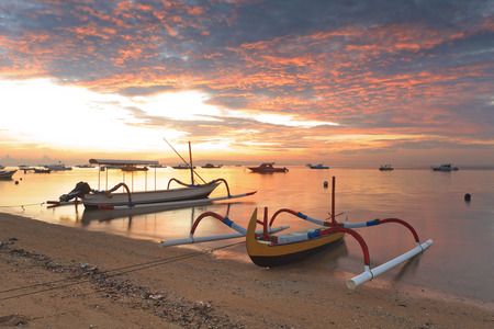 traditional Balinese ships Jukung close on Sanur beach at sunrise, Bali, Indonesiaの写真素材