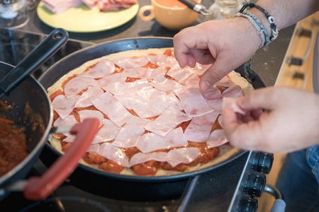 Preparation of authentic homemade cheese pizza with ham in home environmentの写真素材