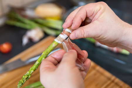 Wrapping green asparagus with baconの写真素材