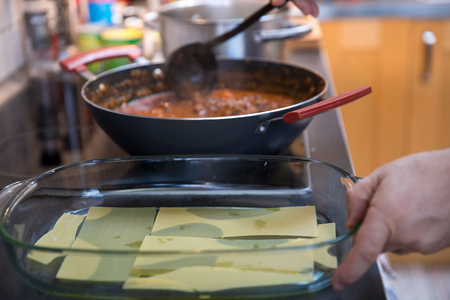 Preparation Lasagna with beef ragout sauce or Lasagna bolognese with cheese on white plate and wooden backgroundの写真素材