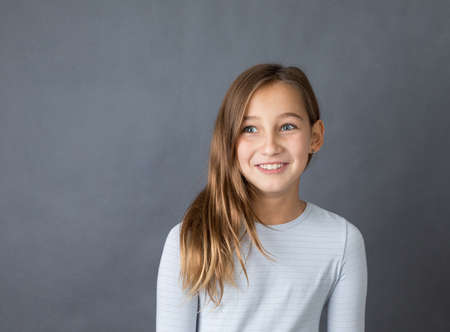 Portrait of a young happy girl on grey background with space for textの写真素材