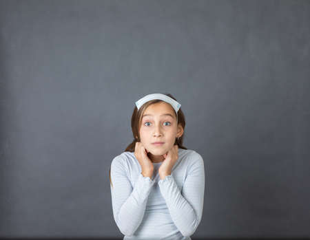 Portrait of a young girl with medical mask on hear head on grey background.の写真素材