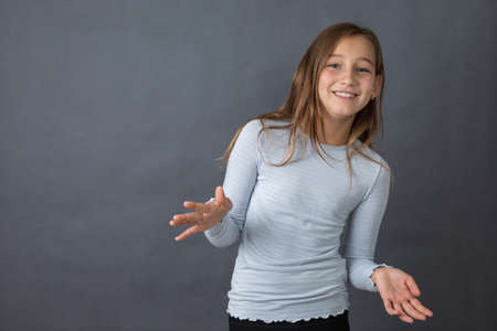 Portrait of a young happy girl on grey background with space for textの写真素材