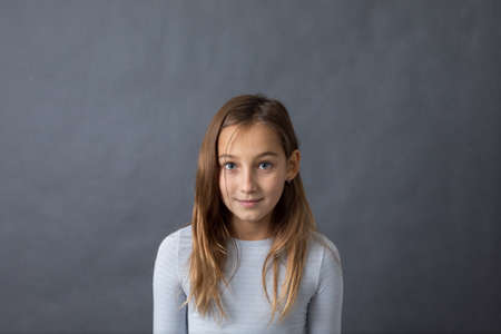 Portrait of a young happy girl on grey background with space for textの写真素材
