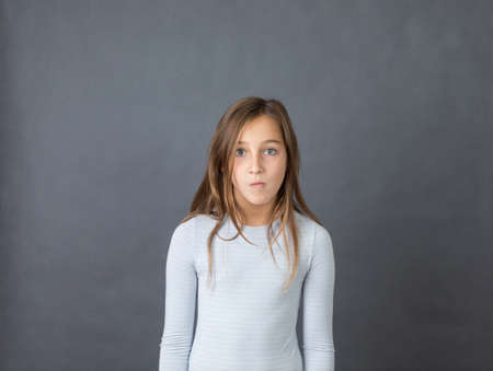 Portrait of a young suprised girl on grey background.の写真素材