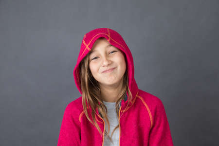 Portrait of a young happy girl in red sweater on grey background with space for textの写真素材