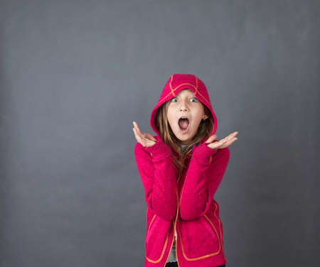 Portrait of a young happy girl in red sweater on grey background with space for textの写真素材