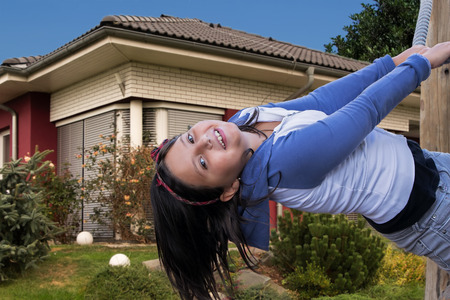 Happy young girl playing on playground in the garden in front of her home.の写真素材