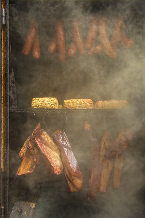 Indian corn, homemade sausages, cheese and ham in barbecue smoker.の写真素材