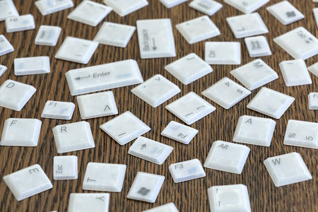 Different computer keys lying on a wooden table.