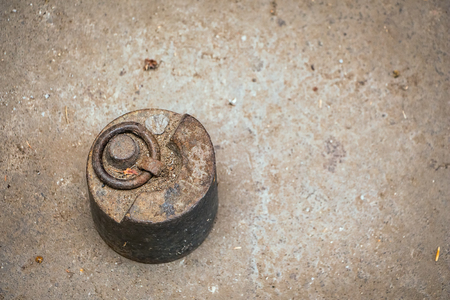 Old antique weight, 5 kg, on dirty grunge floor.の写真素材