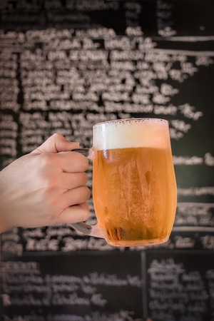 Cheers, one bear in traditional Czech pub with chalk menu on blackboard as backgroundの写真素材