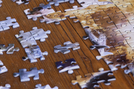 Scattered pieces of jigsaw puzzle on wooden table. Effort to fit thing together.の写真素材