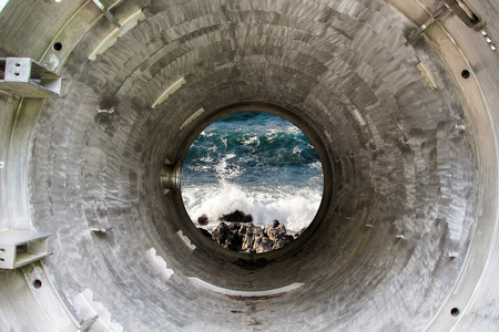 Deep iron tunnel or tube toward the sea, industrial view.の写真素材