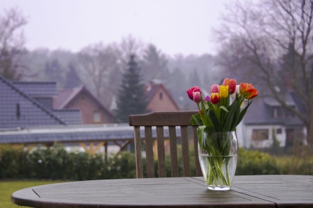 colourful tulips in a vase outside on a tableの写真素材
