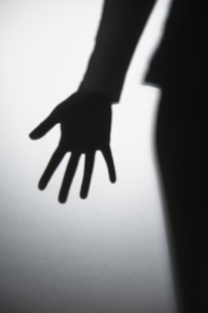 a womand hand silhouetted behind frosted glassの写真素材