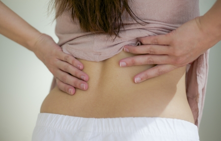 woman has her hand on back due to acheの写真素材