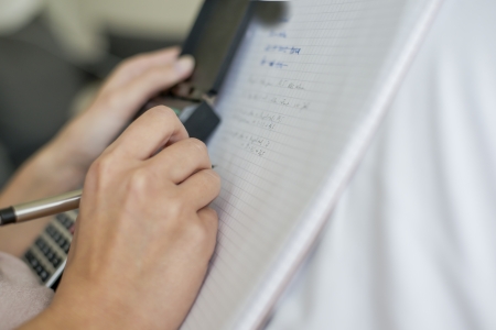 woman holding a calculator writes on a sheet of paperの写真素材