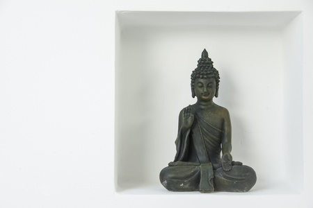a buddha figure with a violet ordhid blossom in a recession on a white wallの写真素材