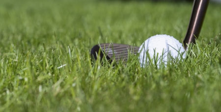 a wedge is positioned behind a moist golfball in the grassの写真素材
